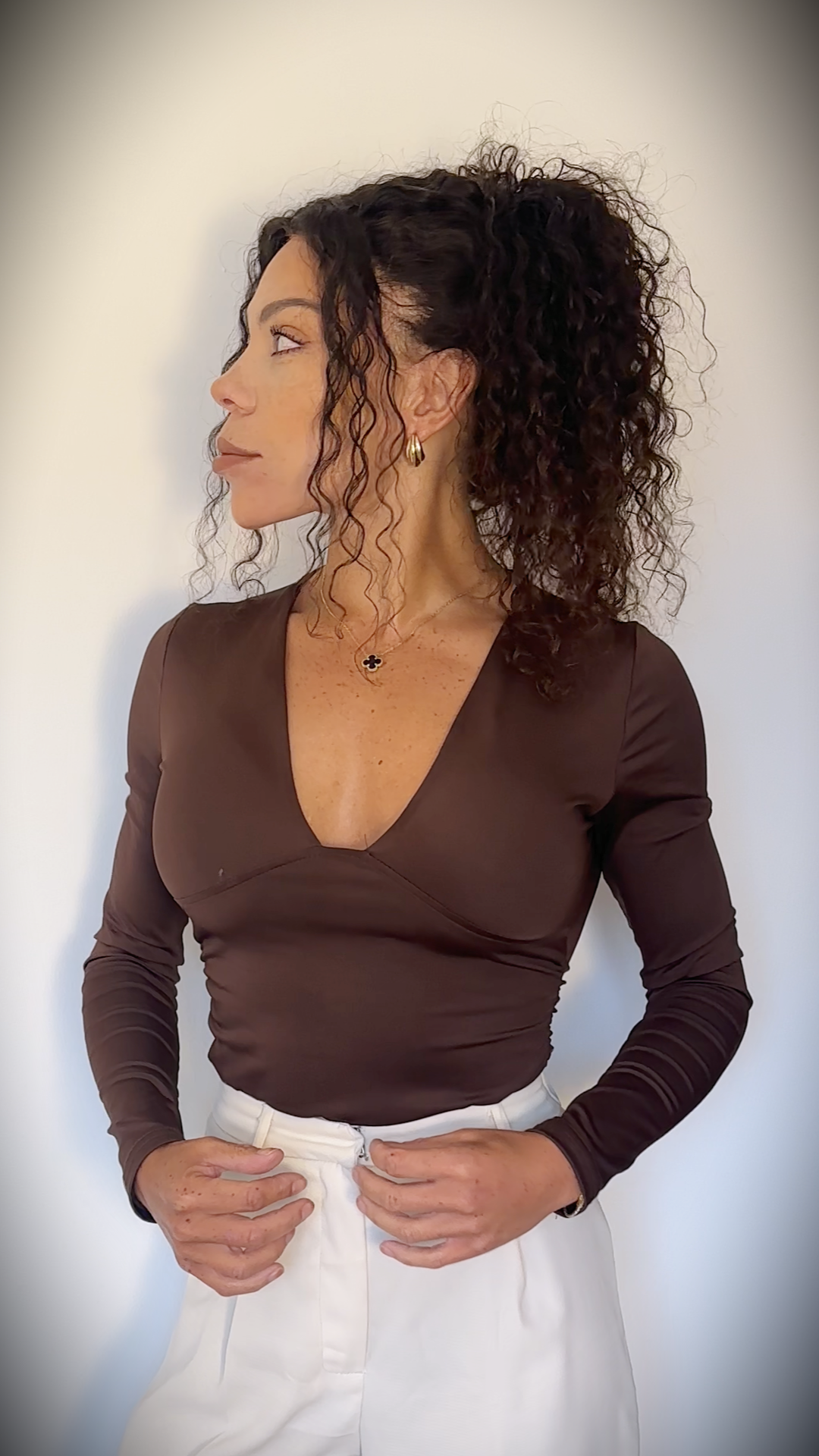 Founder portrait in warm tones — A warm, premium founder‑style portrait of Natalie standing confidently in a brown knit top against a neutral background.